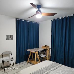 a bedroom with a ceiling fan and blue curtains at Le temps d'une pause ! Petit-déjeuner inclus ! in Servas