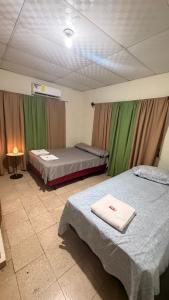 two beds in a room with green curtains at Hostal Flores in David