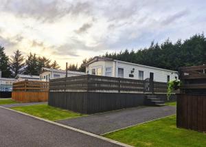a white house with a fence and a house at Dornoch Holiday Chalet in Proncy