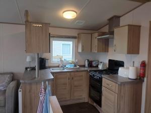 a small kitchen with wooden cabinets and a stove at Dornoch Holiday Chalet in Proncy