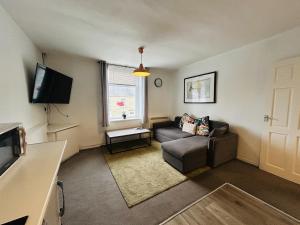 a living room with a couch and a television at Cosy Flat - Over Arch in Oswaldtwistle
