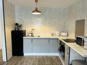 a kitchen with white cabinets and a black refrigerator at Cosy Flat - Over Arch in Oswaldtwistle