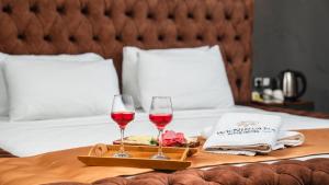 two glasses of red wine on a tray on a bed at We Nirvana Otel in Mezitli