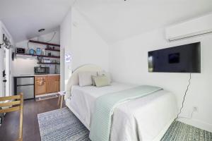 a white bedroom with a bed and a tv at Twilight Ranch Tiny Homes - pet friendly & hill country views in Fredericksburg