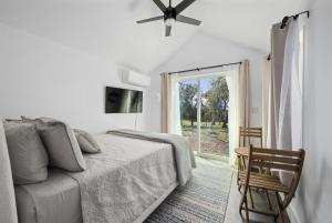 a white bedroom with a bed and a window at Twilight Ranch Tiny Homes - pet friendly & hill country views in Fredericksburg