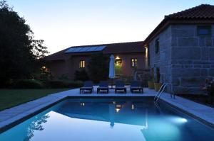 a swimming pool in front of a house at Quinta do Santinho in Amarante