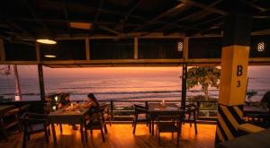 a woman sitting at a restaurant with a view of the ocean at Sea View Varkala Beach Resort in Varkala