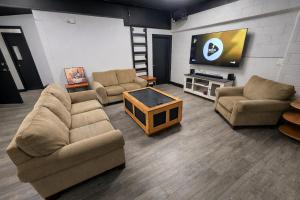 a living room with couches and a flat screen tv at Private Suite, King Bed, Big Screen Sleeps 4 in Hamilton