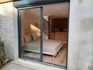 a glass window of a bedroom with a bed at Cottage with large garden in Rieumajou