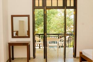 a room with glass doors and a table and a mirror at AYUBELLO hostel & suites in Ahungalla