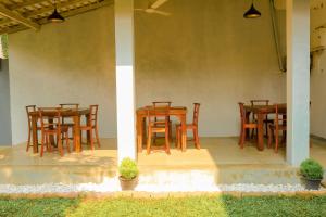 a group of wooden tables and chairs on a patio at AYUBELLO hostel & suites in Ahungalla