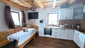 a kitchen with white cabinets and a table in it at Chata Relax 1 in Pribylina +12 photos