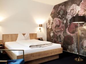 a bedroom with a bed with a floral wall at DORMERO Hotel Crailsheim in Crailsheim +9 photos