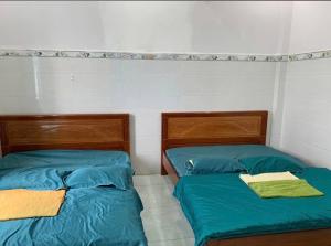 two beds sitting next to each other in a room at Khách Sạn Vinhomes Huỳnh in Phú Nhuận