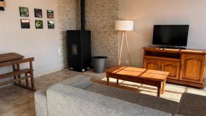 a living room with a couch and a flat screen tv at Maison de Campagne in Chasnay
