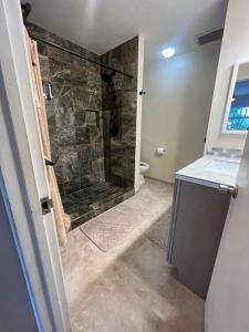 a bathroom with a shower with a stone wall at Beachfront 1 Bedroom Condo with Private Beach, Pool, Hot Tub in Pahala