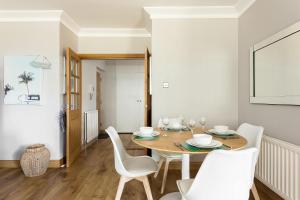 a dining room with a wooden table and white chairs at Sandy Shores - Moments from Blue Flag Sandbanks Beach in Poole