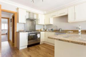 a kitchen with white cabinets and a stove top oven at Sandy Shores - Moments from Blue Flag Sandbanks Beach in Poole