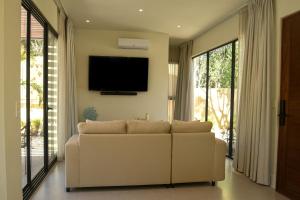 a living room with a white couch and a flat screen tv at Casa Edén in Xpu Ha