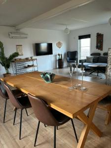a wooden dining room table with chairs and a living room at Oasen in Nørresundby