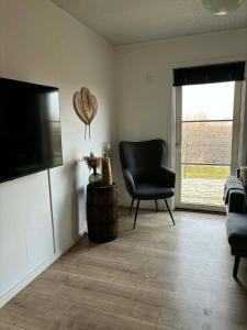 a living room with a chair and a television at Oasen in Nørresundby