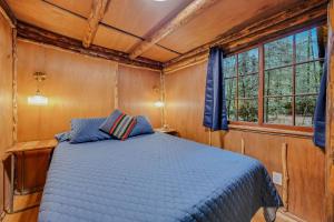 a bed in a room with wooden walls and windows at Mountain Air Cabin in Welches