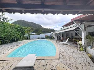 a swimming pool with chairs and a house at Villa Soleïa in Gourbeyre