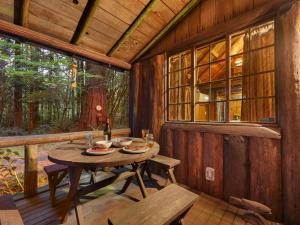 a wooden cabin with a table and benches on a porch at Mountain Air Cabin in Welches