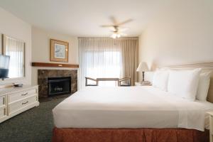 a bedroom with a large white bed and a fireplace at The Monarch Resort in Pacific Grove