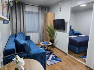 a living room with a blue couch and a bed at Moderna smeštaj Kula in Kula