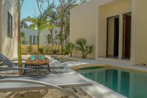 a swimming pool with chairs next to a building at Casa Edén in Xpu Ha