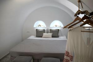 a white bedroom with a bed with two windows at Enalios House in Vourvoúlos