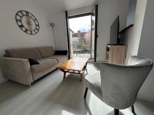 a living room with a couch and a table and a clock at Appartement terrasse en ville in Blois