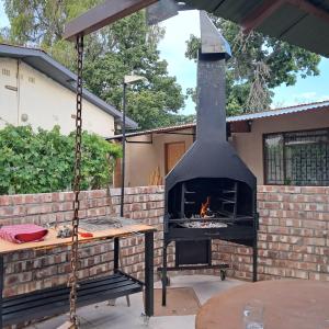 a fireplace in a backyard with a table and a swing at Okahandja Guesthouse in Okahandja