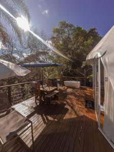 a wooden deck with a table and an umbrella at GOAT LODGE Domo Pitanga in Ibiúna +13 photos