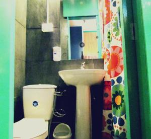 Un baño con lavabo, inodoro y espejo. en La Casa Azul Hostel, en Valparaíso