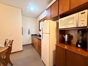 a kitchen with a white refrigerator and a microwave at Apto Rua Coberta Gramado in Gramado