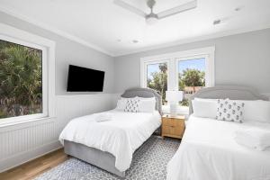 a white bedroom with two beds and a tv at Jungle House-Heated Pool-Pet Friendly-Luxury in Edisto Island +37 photos