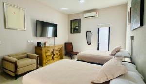 a hotel room with two beds and a chair at Kundera Hotel Boutique in Colima