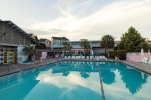 a large blue swimming pool with white chairs in front of a building at The Trendy In Park Circle Mins to DT CHS & Beach in Charleston