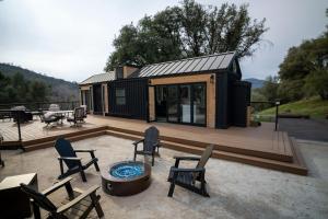 a black tiny house with a deck and chairs at River Falls Retreat in Oakhurst