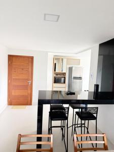 a kitchen with a black counter top and chairs at Recanto da Praia in Anchieta +35 photos