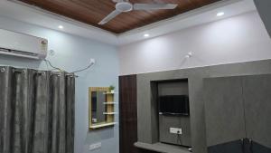 a living room with a tv and a ceiling fan at Deoghar BnB in Deoghar