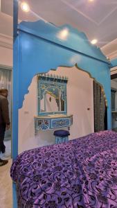 a bed with a purple bedspread and a mirror at L Andalousie in Tabarka