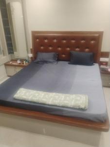 a large bed with a wooden headboard and blue sheets at Vihangam vatika in Sasarām
