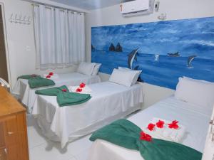 two beds in a room with a painting on the wall at Pousada São Silmares in Fernando de Noronha