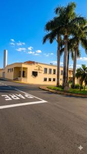 an empty street in front of a building with palm trees at Pindorama Golden Plaza Hotel - Pindorama SP in Catanduva