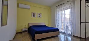 a bedroom with a blue bed and a window at Casa Vacanze Samelia in Altavilla Milicia