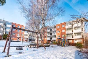 a playground in the snow in front of a building at Kalastajankuja Apartment in Espoo