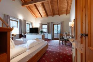 a bedroom with a bed and a desk and a table at Hotel Neuhäusl - herzlich familiär in Berchtesgaden